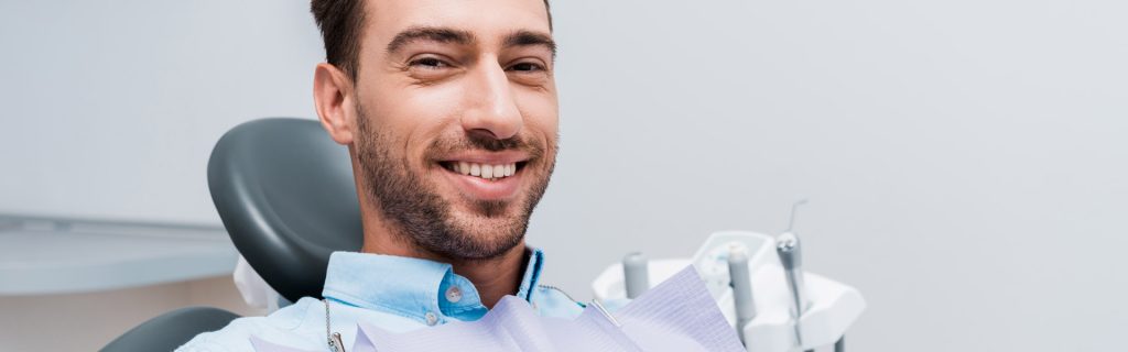 A bearded man is happily smiling and giving a thumbs-up in the dental clinic